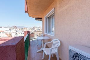 einen Balkon mit 2 Stühlen, einem Tisch und einem Fenster in der Unterkunft MalagaSuite Pier Fuengirola in Fuengirola