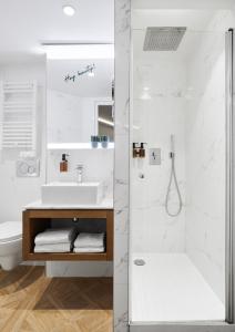 La salle de bains blanche est pourvue d'un lavabo et d'une douche. dans l'établissement Hotel Petit Lafayette, à Paris