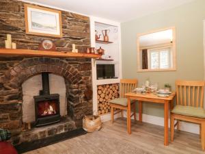 a living room with a stone fireplace and a table at Vigo Cottage in Tavistock