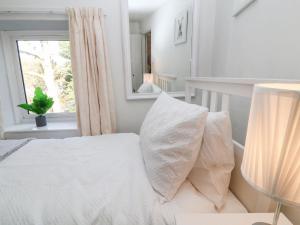 a white bedroom with a bed with pillows and a window at Vigo Cottage in Tavistock