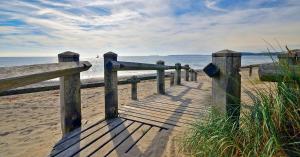 a wooden boardwalk on the beach near the ocean at Finest Retreats - Peace Retreats Penthouse in Pwllheli