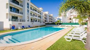a swimming pool in front of a building with lounge chairs at Central Albufeira Great Location 