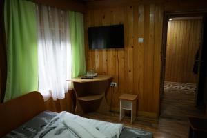 1 dormitorio con 1 cama y escritorio con TV en Cabana Suprema Armonie, en Dîmbovicioara