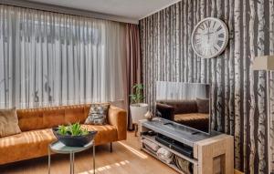 a living room with a couch and a clock on a wall at Huis Kleur in Grubbenvorst