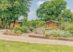 a bench in the middle of a garden with houses at Herons Brook Retreat Lodges in Narberth