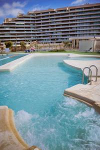 a swimming pool in front of a large building at Los Flamencos - Playa Paraíso - Calle Bomilcar in Cartagena