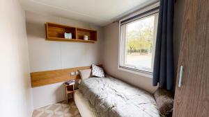Cette petite chambre comprend un lit et une fenêtre. dans l'établissement Camping Officiel Siblu Les Viviers, à Lège-Cap-Ferret