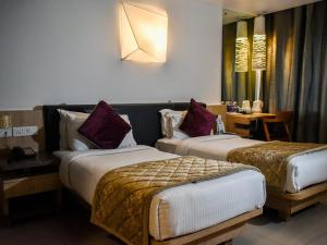 a hotel room with two beds and a table at Nexstay Asma Tower in Kozhikode