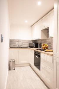 una cucina con armadi bianchi e un cesto di frutta di Ridley House Apartments a Yarm
