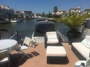 einen Balkon mit Stühlen und einem Boot auf dem Wasser in der Unterkunft Marina Aigues Mortes 75m2 in Aigues-Mortes