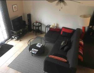a living room with a black couch and a television at Marina Aigues Mortes 75m2 in Aigues-Mortes