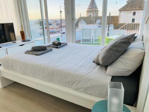 een groot bed in een kamer met een groot raam bij Ático Cádiz 360 in Cádiz