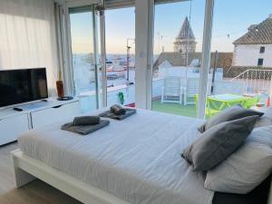 a bedroom with a bed with pillows and a large window at Ático Cádiz 360 in Cádiz