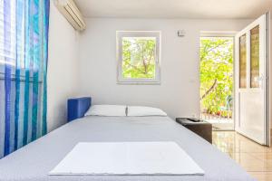 a white bedroom with a bed and a window at Apartment Adrian in Baška Voda