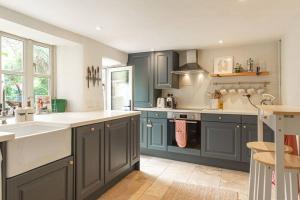 una cocina con armarios azules y encimeras blancas en Charming Country Cottage Near Nailsworth en Box