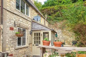 a stone house with two potted plants on a porch at Charming Country Cottage Near Nailsworth in Box