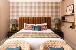 a bedroom with a bed with two chairs and two lamps at The Tophams Hotel in London