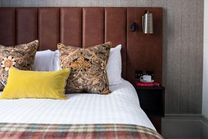 a bedroom with a bed with pillows and a headboard at The Tophams Hotel in London