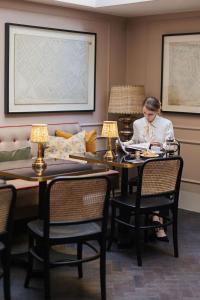 a woman sitting at a table reading a book at The Tophams Hotel in London