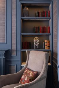 a chair with a pillow in front of a book shelf at The Tophams Hotel in London