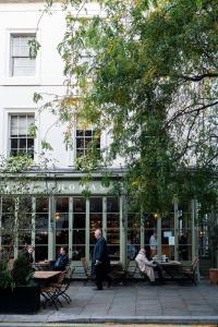 a group of people sitting at tables in front of a building at The Tophams Hotel in London