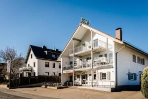 ein weißes Gebäude mit Balkon auf der Seite in der Unterkunft Hotel am See in Kreuzau