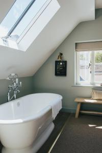 a white bath tub in a bathroom with a skylight at The Bottle & Glass Inn in Harpsden