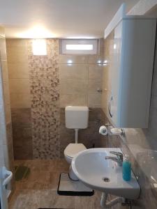 La salle de bains est pourvue d'un lavabo blanc et de toilettes. dans l'établissement Apartmani Most, à Trebinje