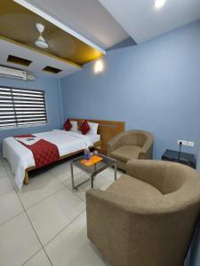 a bedroom with a bed and a couch and a table at Sharp Suites in Ernakulam