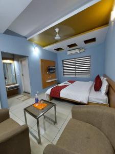 a bedroom with a bed and a couch and a table at Sharp Suites in Ernakulam