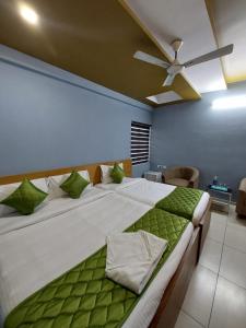 a bedroom with a large white bed with green pillows at Sharp Suites in Ernakulam