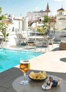 una copa de vino y patatas fritas en una mesa junto a una piscina en Vincci Molviedro en Sevilla