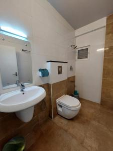 a bathroom with a white sink and a toilet at Sharp Suites in Ernakulam