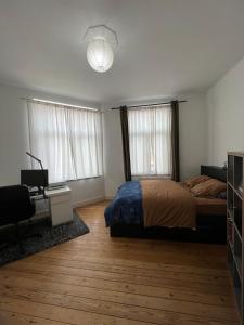 a bedroom with a bed and a desk and two windows at L Escapade Urbaine in Brussels