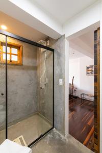 una puerta de ducha de cristal en una habitación con suelo de madera en Loft do Serjoca, en São Paulo