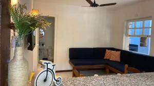 a living room with a blue couch and a vase with a bike at Casa Búzios Villas Centro Búzios in Búzios