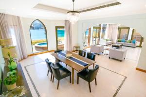 a dining room with a table and chairs and a living room at FAM Living - Palm Jumeirah - Beach Villas with Private Pool in Dubai