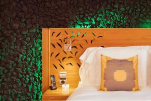 Bett mit einem Kopfteil aus Holz mit Vögeln an der Wand in der Unterkunft Bohemia Suites & Spa - Adults Only in Playa del Ingles