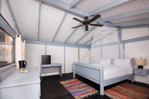 um quarto com uma cama branca e uma ventoinha de tecto em Conch Beach Cabins 