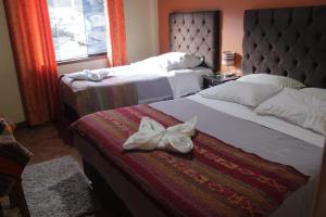 two beds in a hotel room with towels on them at hostal Qorisonqo inn ollantaytambo in Ollantaytambo