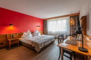 a hotel room with a bed with a red wall at Biobausewein WEIN HOTEL LEBEN in Iphofen