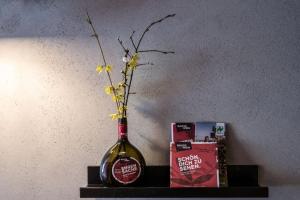 a bottle of wine sitting on a shelf with flowers in it at Biobausewein WEIN HOTEL LEBEN in Iphofen