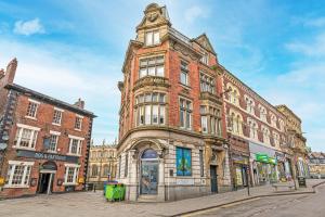 an old brick building with a clock tower on a street at Wigan Central Serviced Apartments in Wigan