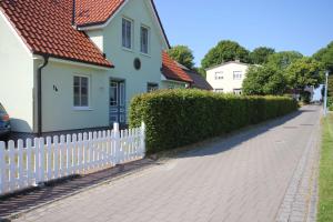 una casa con una cerca blanca al lado de una calle en Am Meer Backbord, en Wustrow