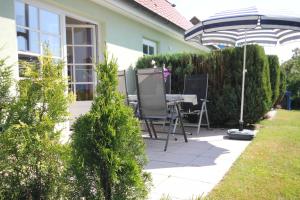 Un patio con una mesa y sillas bajo una sombrilla. en Am Meer Backbord, en Wustrow