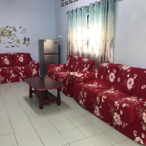 a living room with red couches and a table at 吉胆岛海甜民宿 Swee Sea Homestay Pulau Ketam in Bagan Teochew
