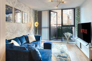 ein Wohnzimmer mit einem blauen Sofa und einem TV in der Unterkunft City Centre Apartment - Ideal for longer stays in Manchester