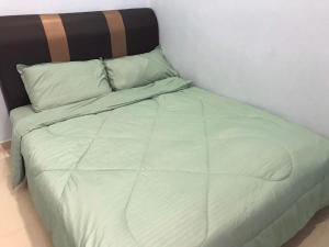 a bed with a green comforter and pillows at 吉胆岛海甜民宿 Swee Sea Homestay Pulau Ketam in Bagan Teochew +2 photos