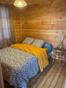 um quarto com uma cama e uma parede de madeira em LA CABANE DE JABI em Trémont