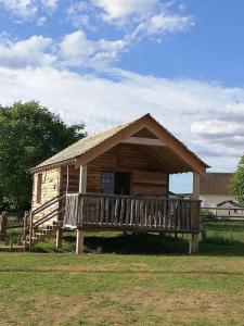 uma pequena cabana de madeira com um alpendre num campo em LA CABANE DE JABI em Trémont
